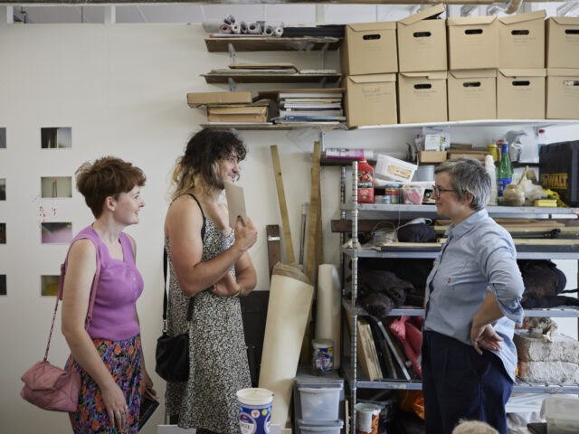 Three people in a London art studio talking.